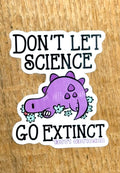 Protest sticker with a purple dinosaur and text 'Don't let science go extinct' on a wooden background by Unfolded Label