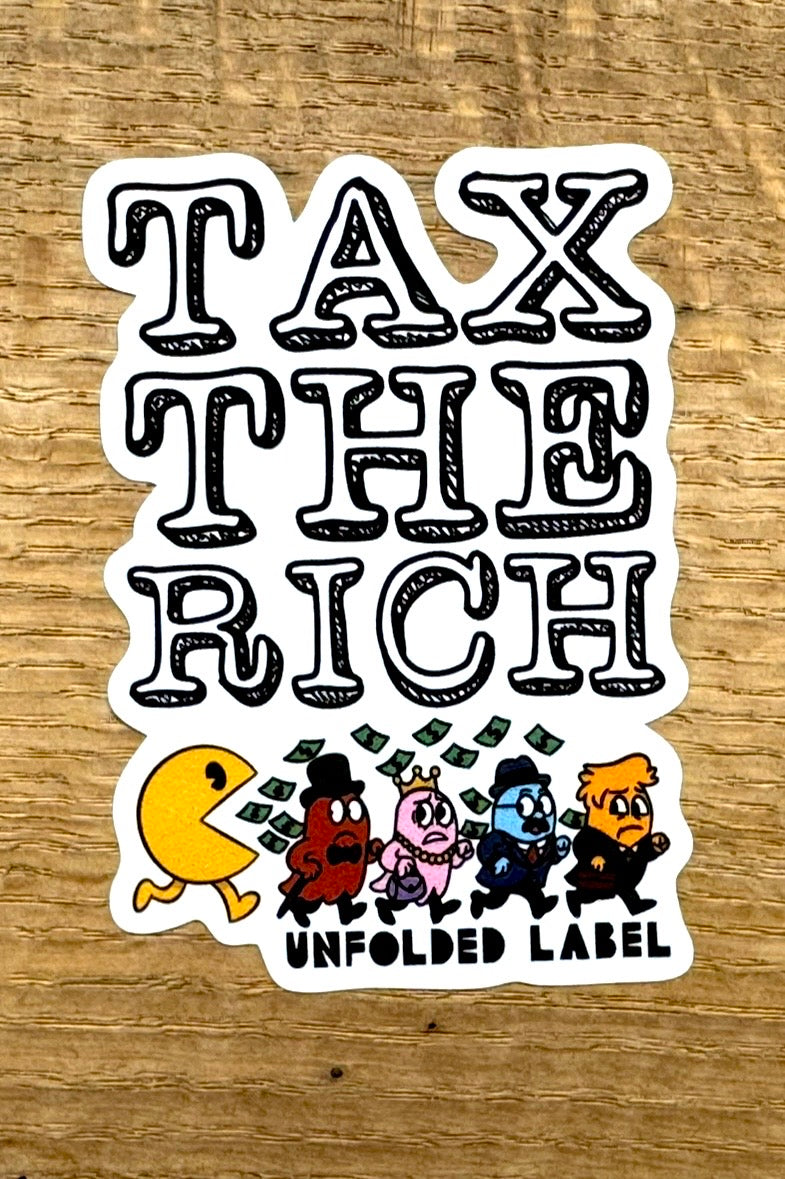Protest sticker with 'Tax the Rich' text and cartoon characters on a wooden surface by Unfolded Label